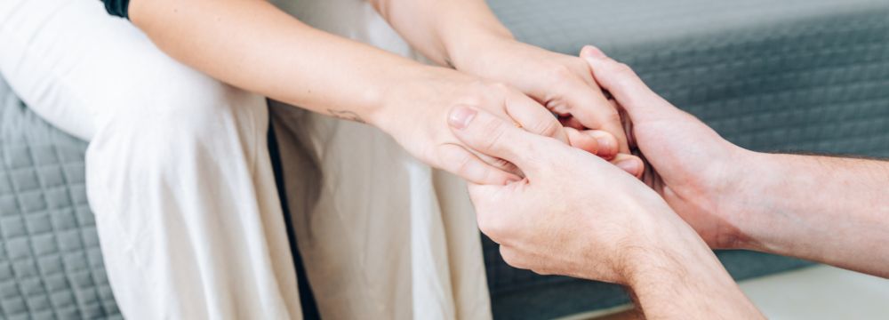 Man holding woman's hands acting as support while battling addiction